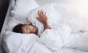 Sleeping, tired and man in bed in home for relaxing