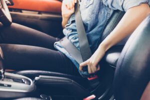 woman fastening seat belt in the car, safety concept