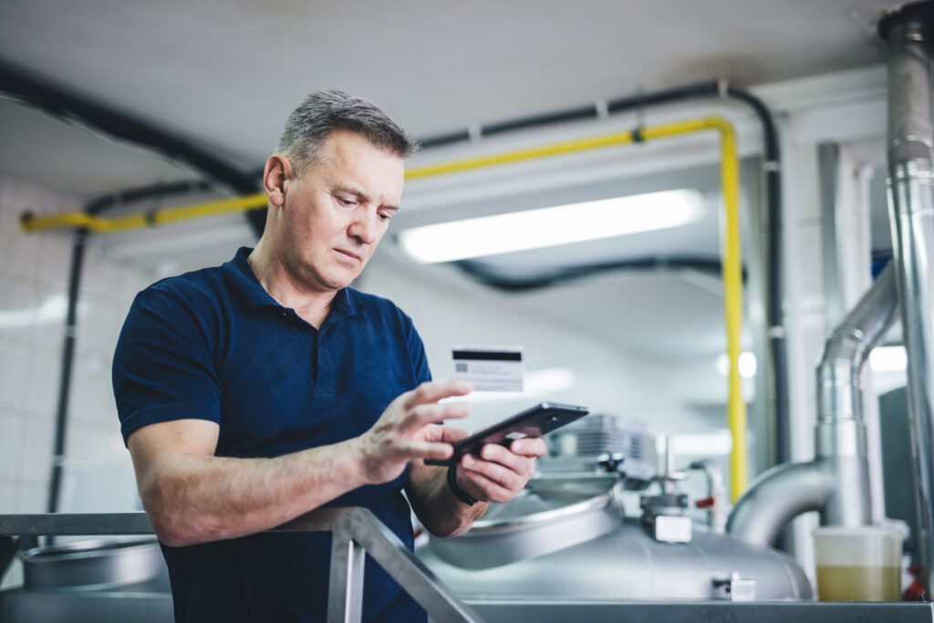 Craft brewery owner or manager paying with mobile phone