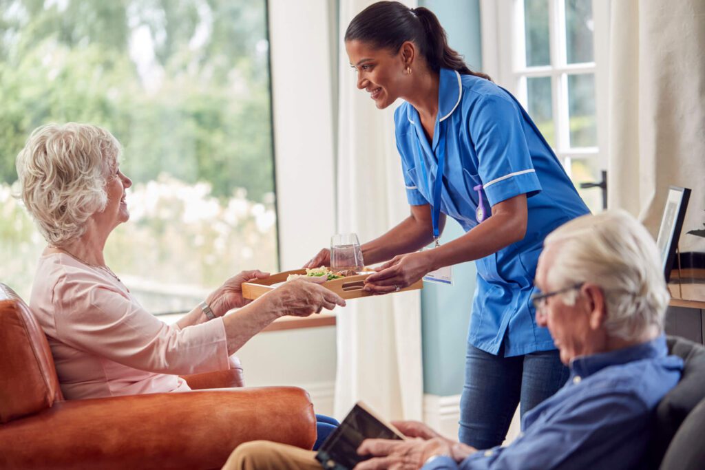 care home nurse serving elderly woman