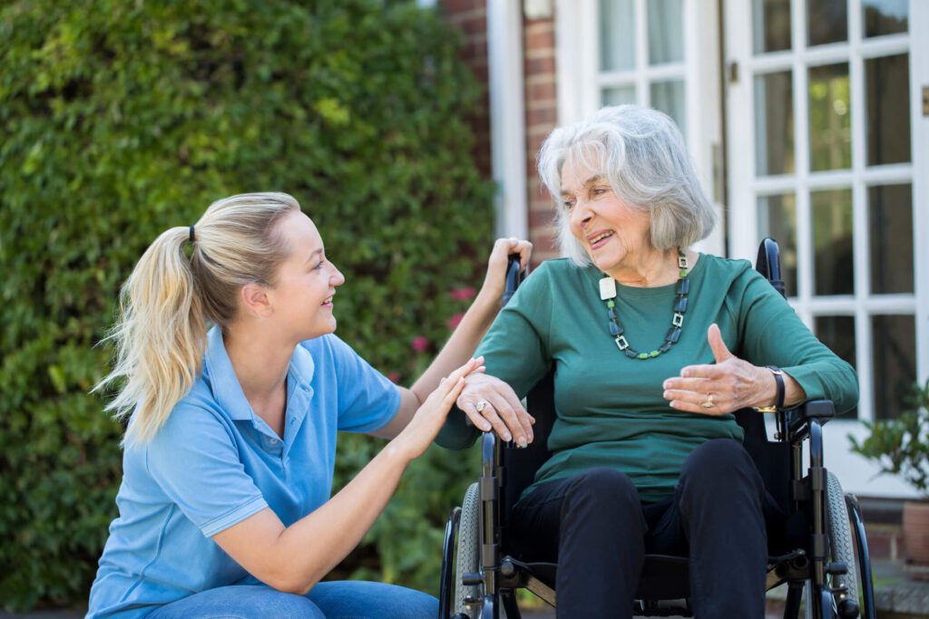 care home nurse tending to woman in wheelchair